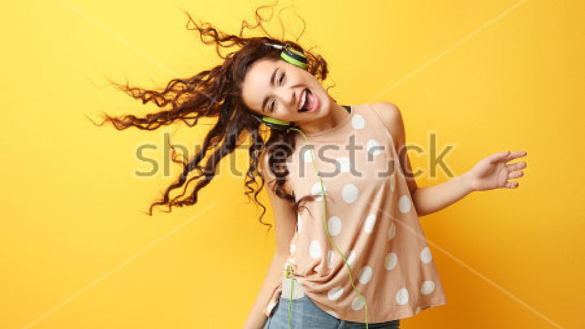 Stock Photo Beautiful Young Woman In Headphones Listening To Music And Dancing On Yellow Background 585033697